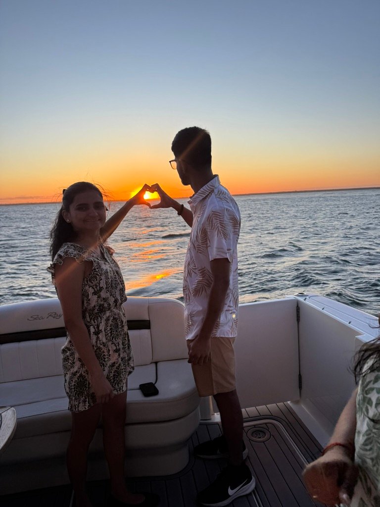 Couple making a heart at sunset on the yacht